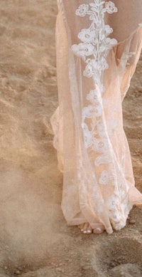 a woman in a white dress walking in the sand