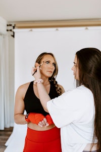 a woman is getting her makeup done by another woman